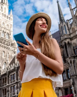 A young woman smiling at her phone in a city square